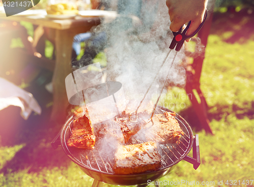 Image of man cooking meat on barbecue grill at summer party