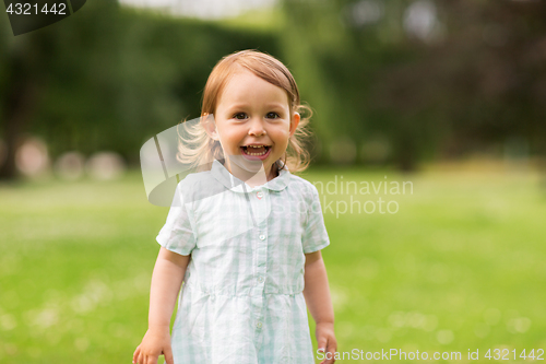 Image of happy baby girl on green summer field