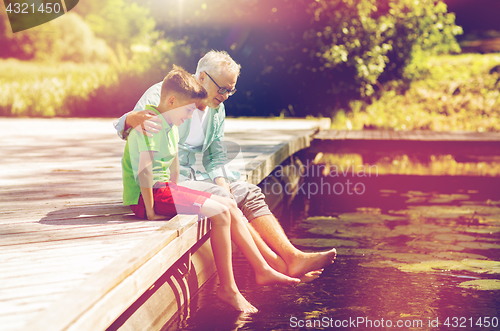 Image of grandfather and grandson sitting on river berth