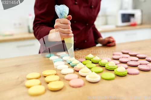 Image of chef with injector squeezing filling to macarons