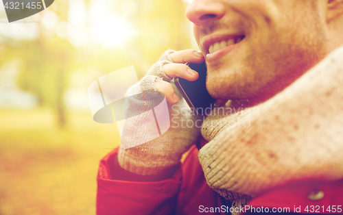 Image of close up of man with smartphone calling in autumn