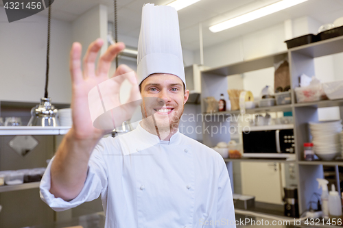 Image of happy chef at restaurant kitchen showing ok sign