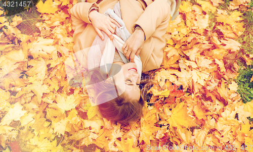 Image of beautiful happy woman lying on autumn leaves