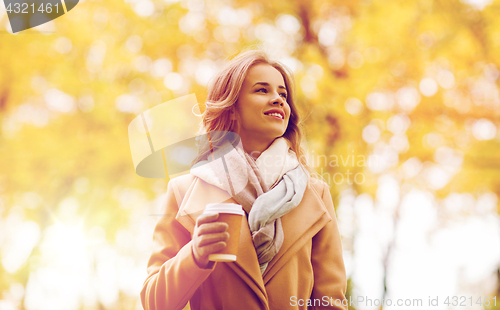 Image of happy young woman drinking coffee in autumn park