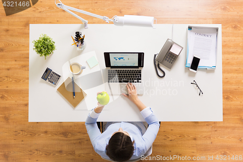 Image of businesswoman with apple and laptop at office