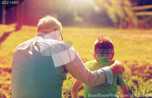 Image of grandfather and grandson hugging outdoors