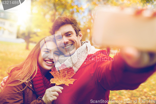 Image of couple taking selfie by smartphone in autumn park