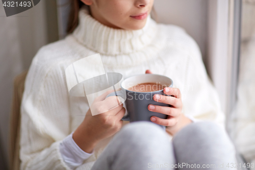 Image of girl with cacao mug looking at home window