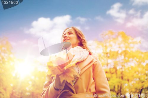 Image of beautiful woman with maple leaves in autumn park