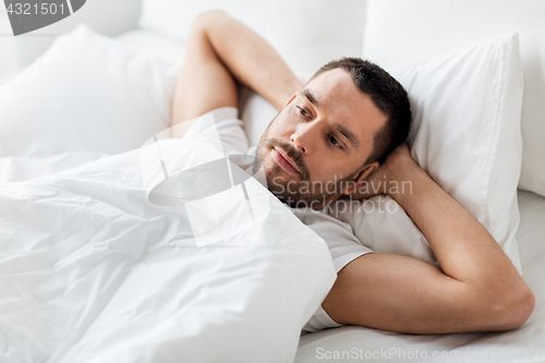 Image of man lying in bed at home