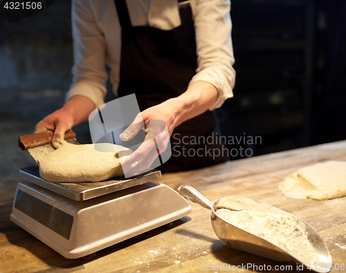 Image of chef or baker weighing dough on scale at bakery