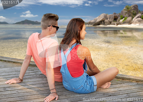 Image of happy teenage couple sitting on river berth