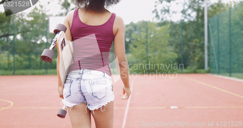 Image of Girl with skateboard on sports ground