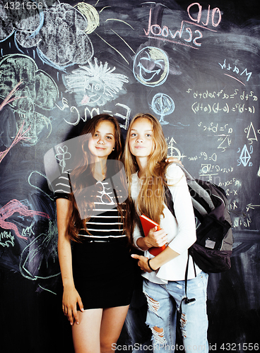 Image of back to school after summer vacations, two teen real girls in classroom with blackboard painted together, lifestyle people concept