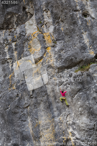 Image of Strong girl climbs on a rock, doing sports climbing in nature.