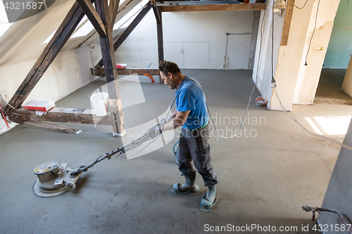 Image of Laborer polishing sand and cement screed floor.