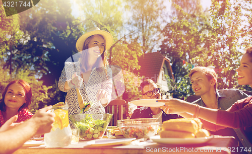 Image of happy friends having dinner at summer garden party