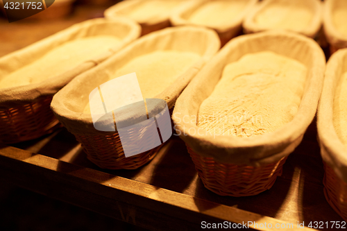 Image of yeast bread dough in baskets at bakery kitchen