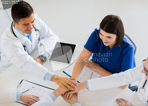 Image of group of doctors holding hands together at table