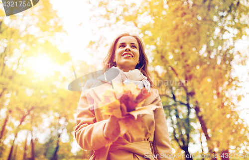 Image of beautiful woman with maple leaves in autumn park