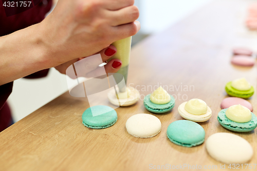 Image of chef with injector squeezing filling to macarons