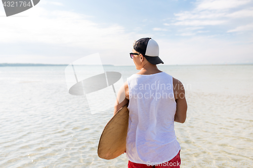 Image of happy young man with skimboard on summer beach