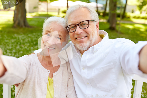 Image of senior couple taking selfie at summer park 