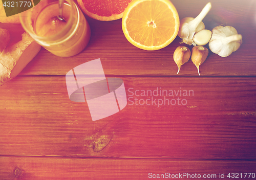 Image of honey, citrus fruits, ginger and garlic on wood