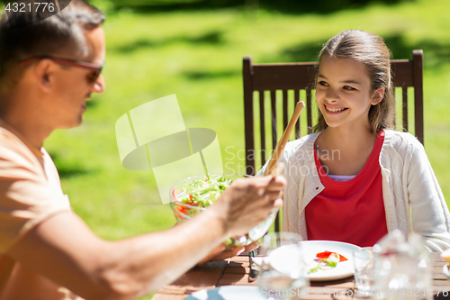 Image of happy girl with father eating at summer garden
