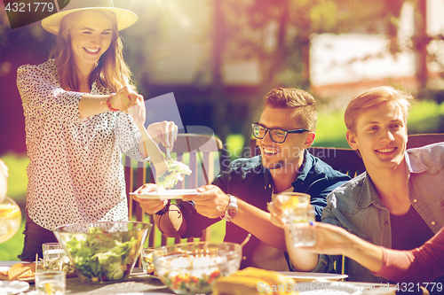 Image of happy friends having dinner at summer garden party