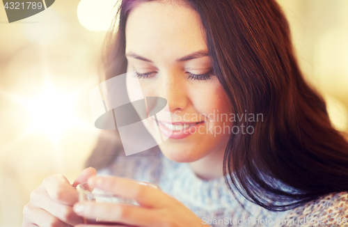 Image of smiling young woman drinking tea at cafe