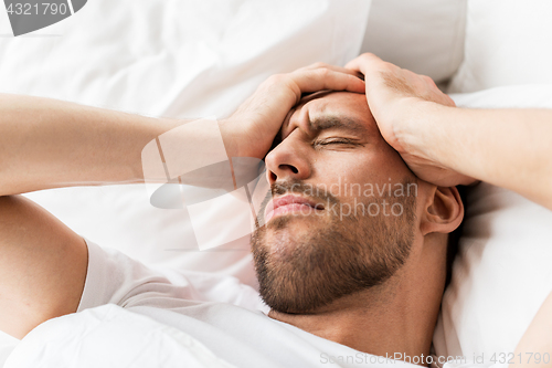 Image of close up of man in bed suffering from headache