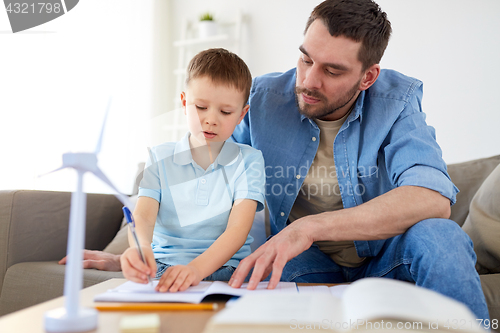 Image of father and son with toy wind turbine at home