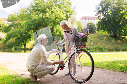 Image of happy senior couple with bicycle at summer park