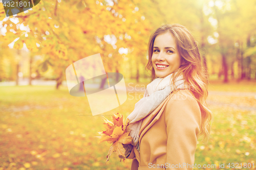 Image of beautiful woman with maple leaves in autumn park