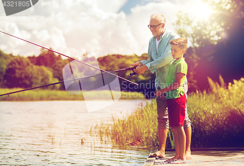 Image of grandfather and grandson fishing on river berth