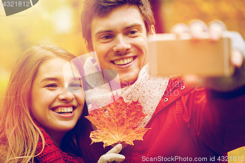 Image of couple taking selfie by smartphone in autumn park