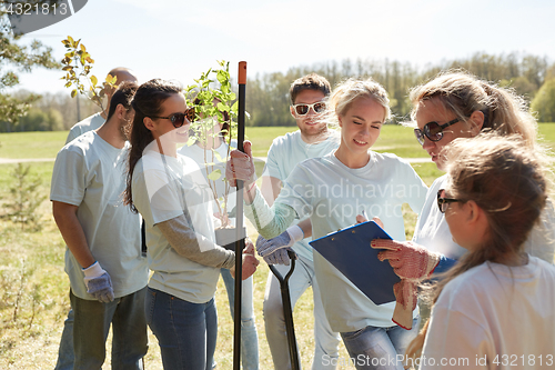 Image of group of volunteers with tree seedlings in park