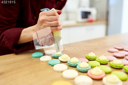 Image of chef with injector squeezing filling to macarons