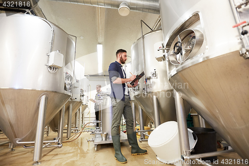 Image of men with clipboard at craft brewery or beer plant