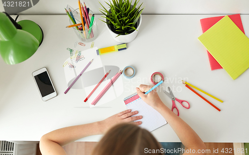 Image of girl drawing in notebook at home