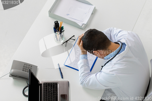 Image of doctor with cardiogram and laptop at clinic