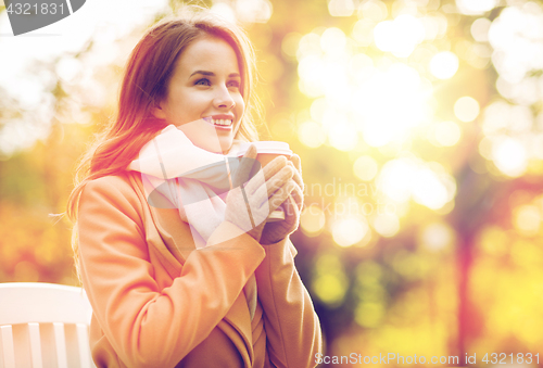 Image of happy young woman drinking coffee in autumn park