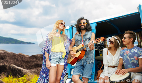 Image of hippie friends playing music at minivan on island