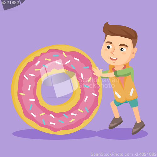 Image of Little caucasian boy rolling a huge sweet doughnut