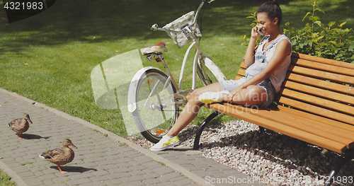 Image of Woman talking phone on bench