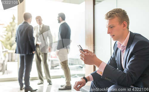 Image of Businessman using smart phone while sitting in waiting room.