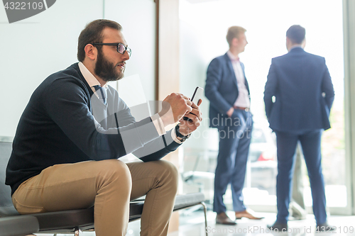 Image of Businessman using smart phone while sitting in waiting room.