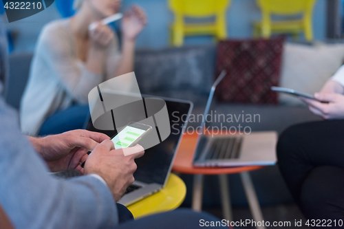 Image of Young casual businessman using smartphone