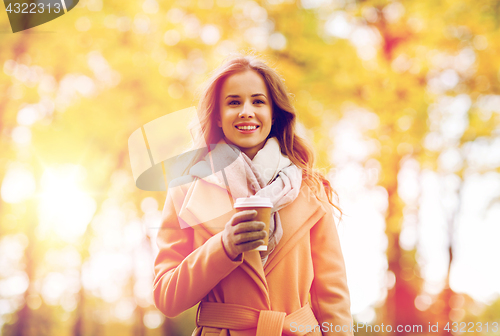 Image of happy young woman drinking coffee in autumn park